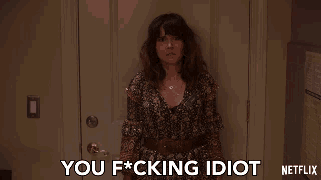 a woman standing in front of a door with the words you fucking idiot written on it