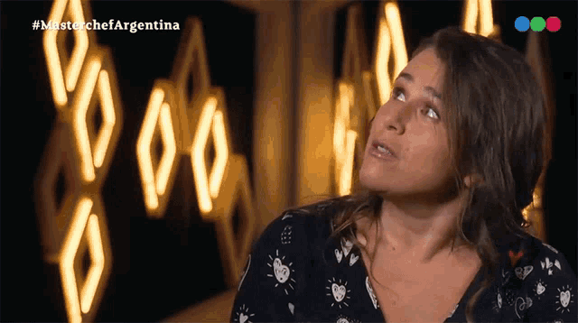 a woman stands in front of a sign that says masterchefargentina
