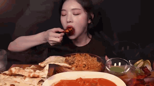 a woman is sitting at a table eating food from a plate .