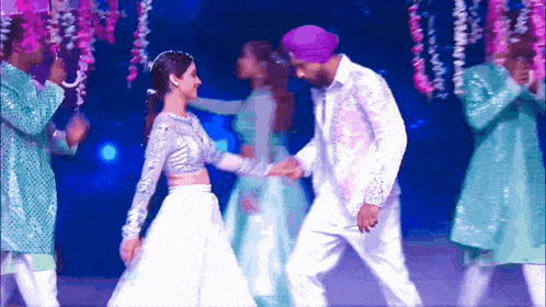 a man in a purple turban is dancing with a woman
