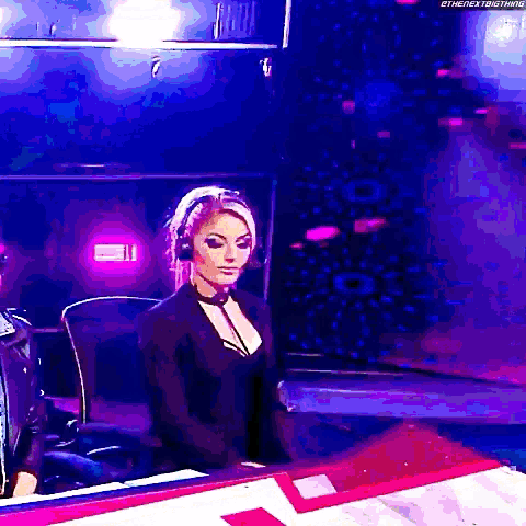 a woman wearing headphones and a choker is sitting in front of a table .