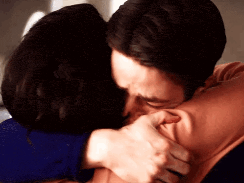 a man is kissing a woman on the cheek while they are hugging each other .