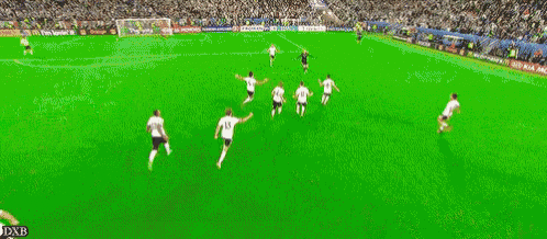 a group of soccer players on a green field with the word dxb on the bottom right