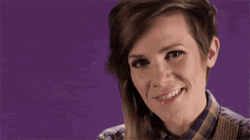 a woman with short hair and a plaid shirt and tie is smiling .