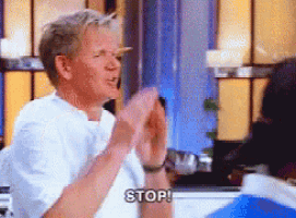 a man in a white shirt is clapping his hands and saying stop