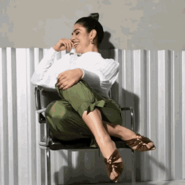 a woman is sitting on a chair with her legs crossed and laughing