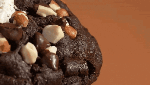 a close up of a chocolate cookie with white chocolate chips and nuts