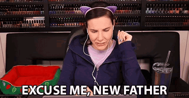 a woman wearing headphones and a cat ear headband says " excuse me new father " while looking at her laptop