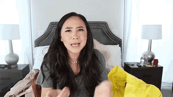 a woman is sitting on a bed with a yellow bag