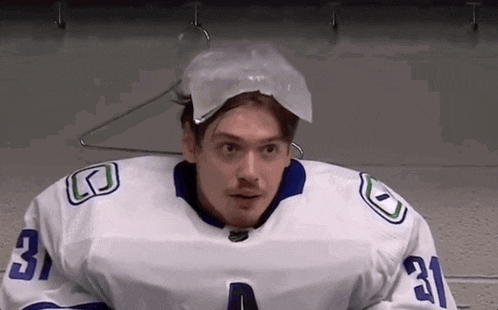 a hockey player with a plastic bag on his head is sitting in a locker room .