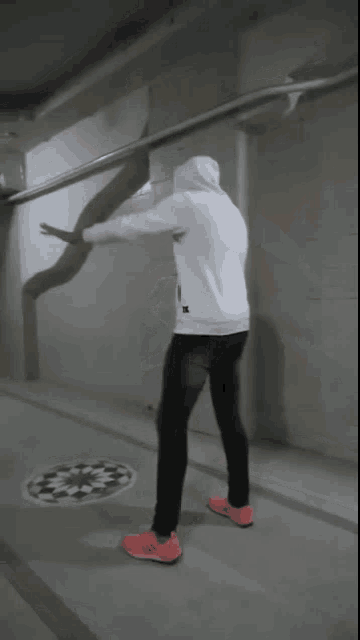 a person wearing a white hoodie and red adidas shoes stands in a hallway