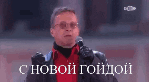 a man in a red shirt is holding a microphone in front of a sign that says " с новой годдой "