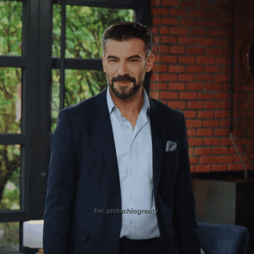 a man in a suit stands in front of a brick wall with a watermark that says tw pistachiogrentv
