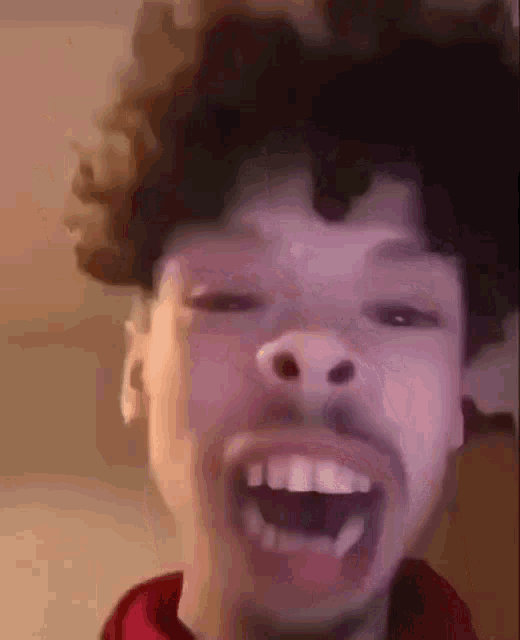 a young man with curly hair is making a funny face .