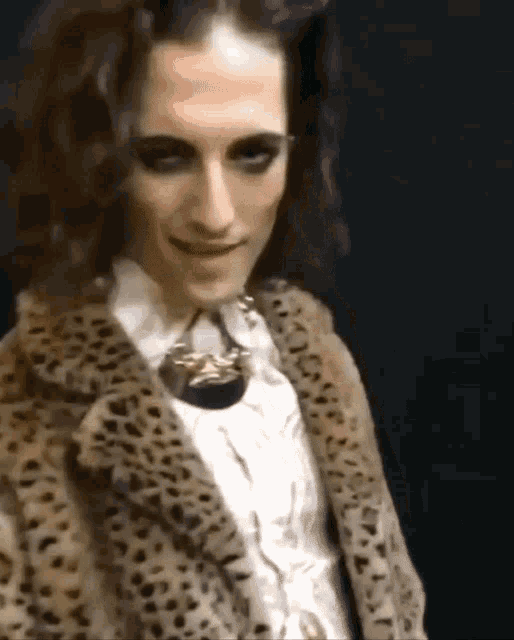 a woman wearing a leopard print fur coat and a necklace is smiling .