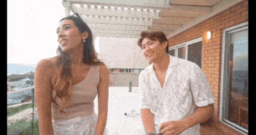 a man and a woman are standing next to each other on a balcony .