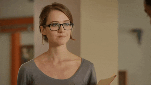 a woman wearing glasses is holding a folder in her hand