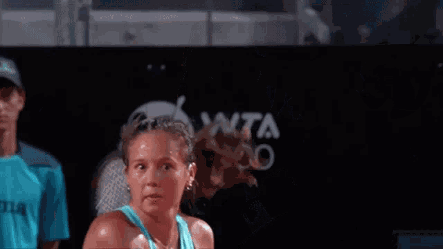 a woman in a blue tank top is holding a tennis racquet in front of a sign that says 10