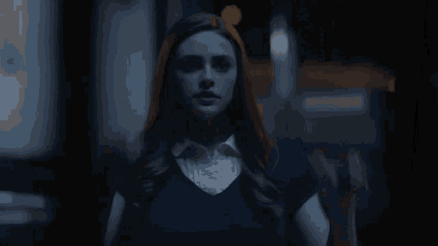 a woman with red hair is standing in a dark room with her hands up .