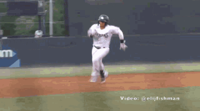 a baseball player is running on a field with a spectrum banner behind him