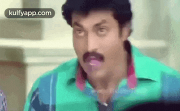 a man with a mustache is making a funny face with his tongue out .