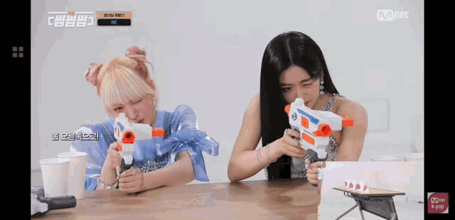 two girls are playing with water guns on a table .
