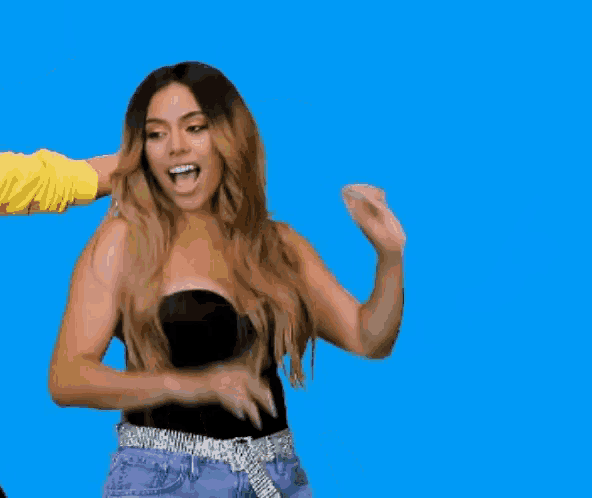 a woman in a black top and purple shorts is dancing with her arms outstretched .