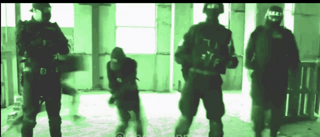 a group of soldiers are standing in a room and one of them has the letter t on his shirt