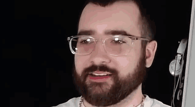 a man with a beard wearing glasses and a chain around his neck .