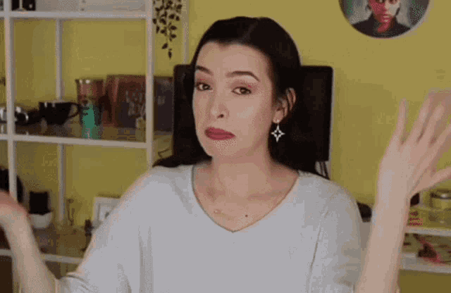 a woman is making a funny face while standing in front of a shelf .