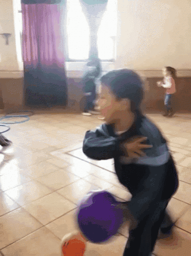 a boy is playing with a purple ball in a room