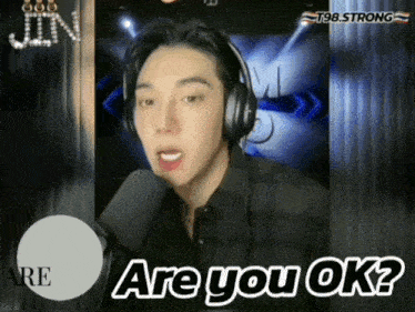 a man wearing headphones says are you ok in front of a microphone