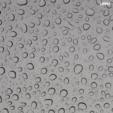 a close up of water drops on a gray surface with luma in the corner