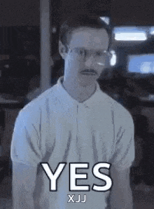 a man with glasses and a mustache is holding his hands up and saying yes .