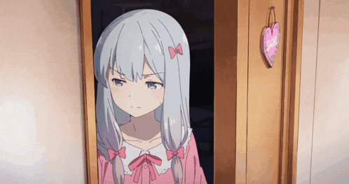 a girl in a pink dress is standing in a doorway with a heart hanging on the wall that says i love you