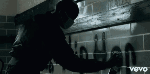 a man spray paints the word " when " on a tile wall