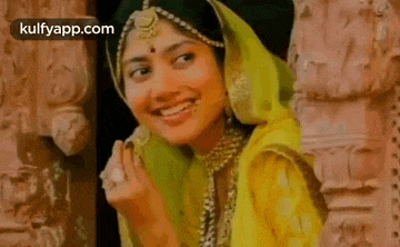 a woman in a yellow dress and green veil is smiling .