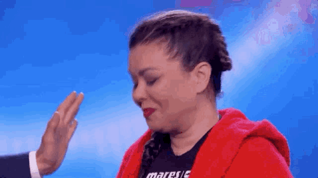 a woman in a red hoodie is giving a high five to a man in a suit .