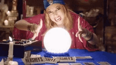 a woman is sitting at a table with a crystal ball and tarot cards .