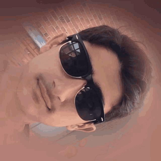 a young man wearing sunglasses and a nose piercing