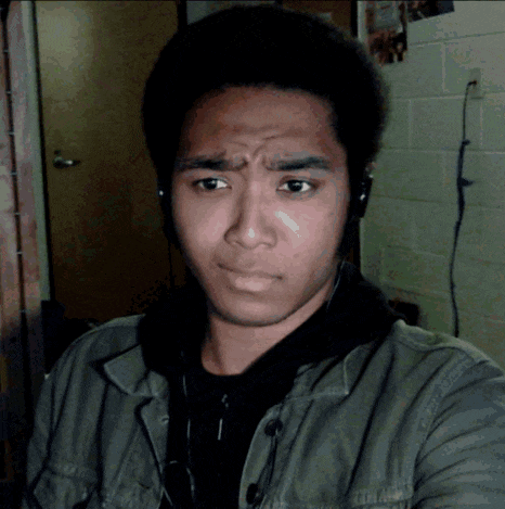 a man wearing headphones and a green jacket makes a face