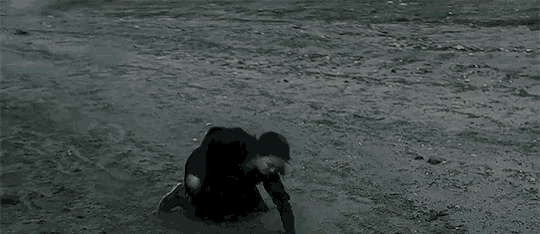 a woman is kneeling on the ground near the water .