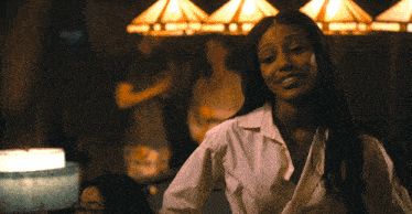 a woman in a white shirt stands in front of a group of people