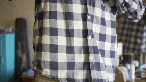 a man wearing a blue and white plaid shirt is standing in a room