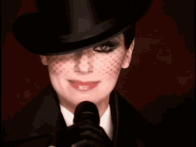 a woman in a top hat and gloves is holding a microphone .