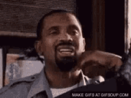 a man with a beard is smiling and making a funny face with his hand .