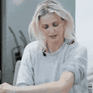 a woman with blonde hair wearing a blue sweater and a necklace
