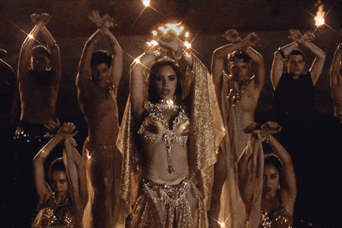 a group of belly dancers are dancing with their hands up in the air