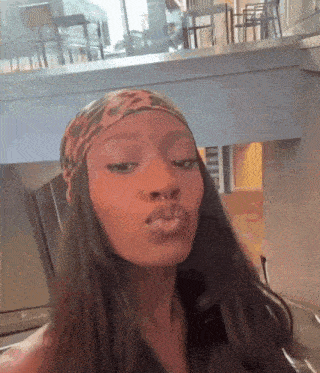 a woman wearing a headband and a nose ring is blowing a kiss .