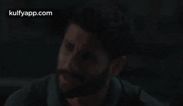 a man with a beard is making a funny face while looking at the camera .